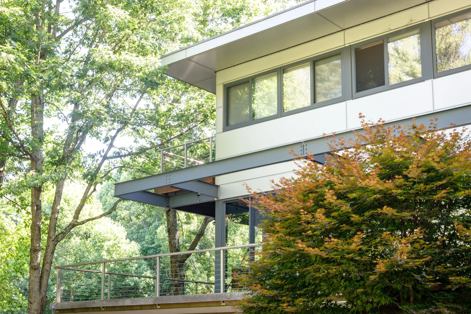 Modern home with a cantilevered upper level and steel beams set among trees