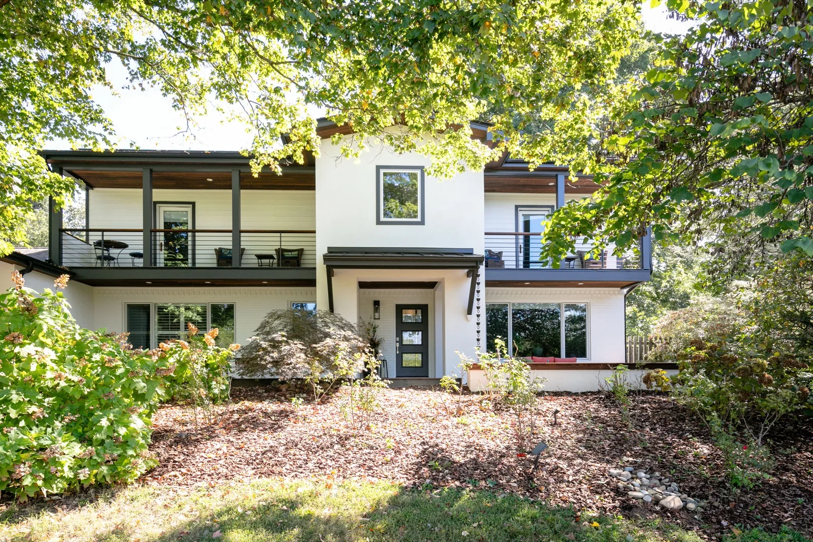 Exterior of a completed home renovation with balconies and a covered entry