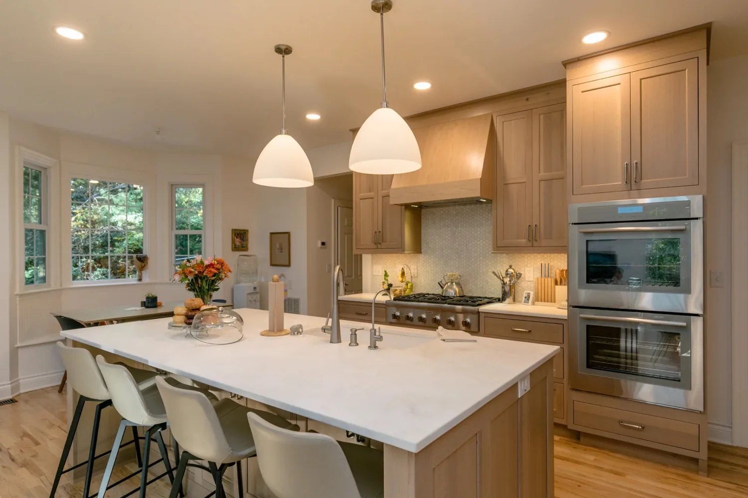Kitchen with a large white island, pendant lighting and double wall ovens