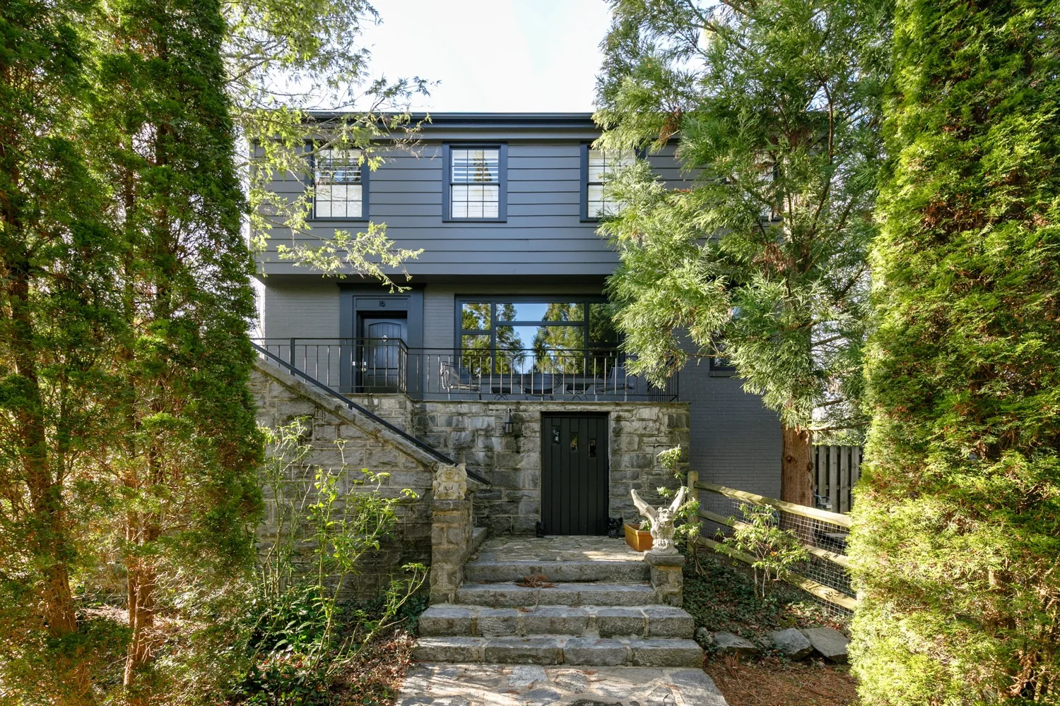 Two-story home with dark siding, a stone foundation and stone steps leading to the entry