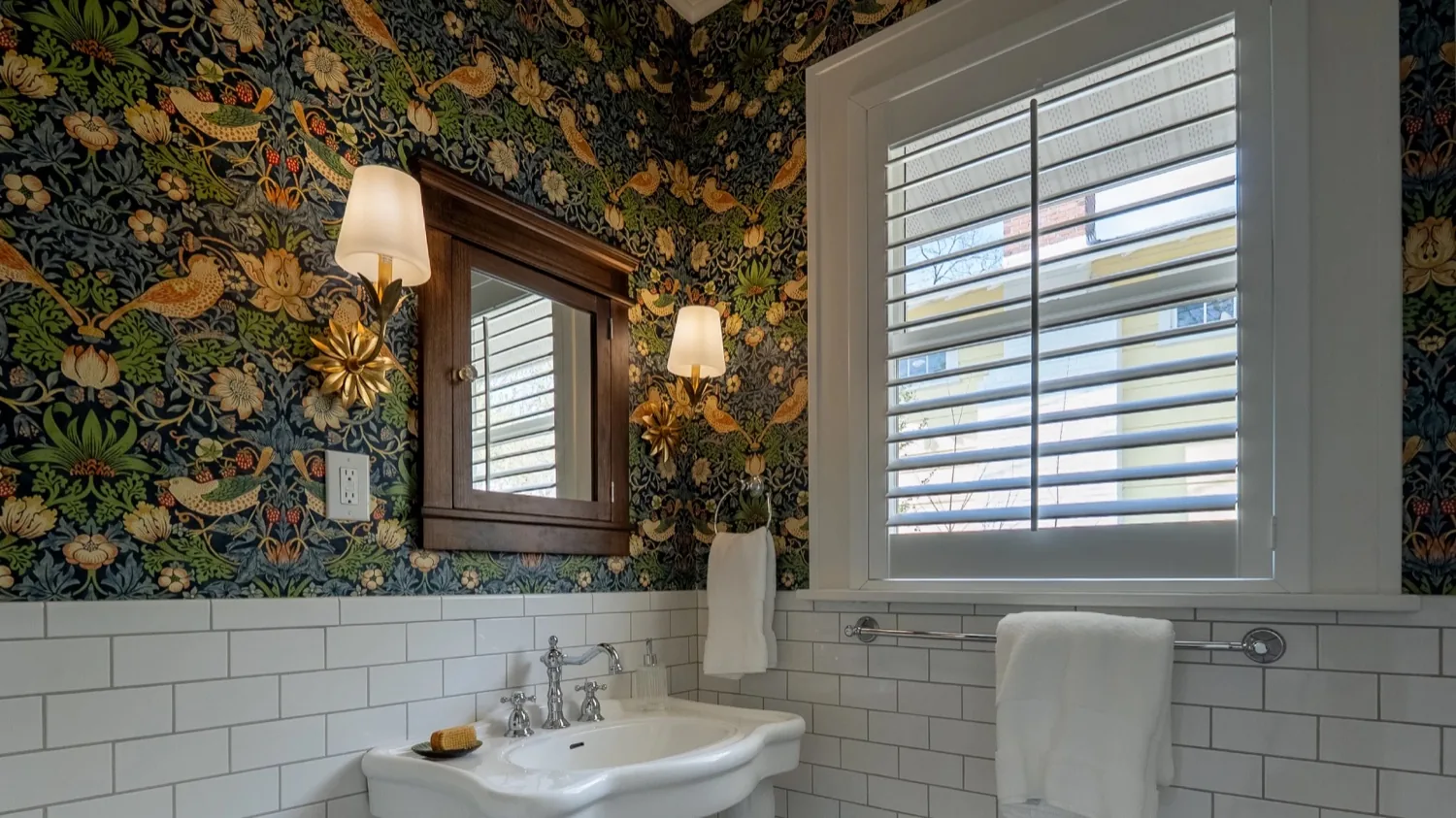 Powder room with botanical wallpaper, white subway tile and a pedestal sink