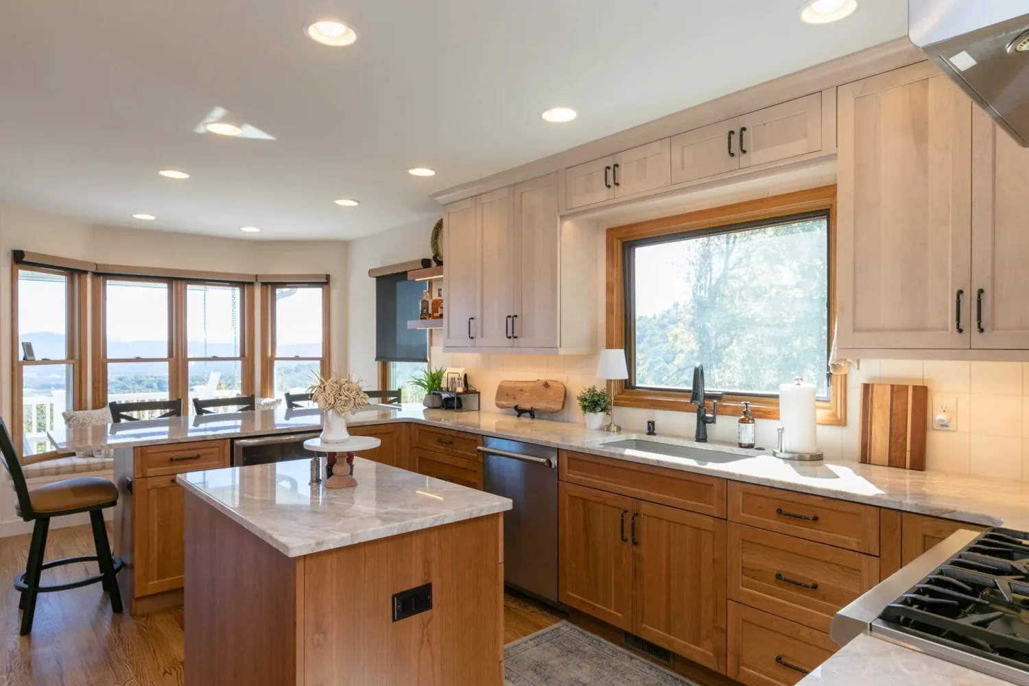 Kitchen with light wood cabinetry, stone counters and a bay window looking out to the valley